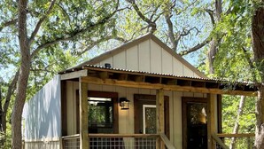 A wooden cabin with a porch, a staircase, and a window. - Aquatic Glamping Vacation in Texas: Luxurious Tented Cabin by the Cibolo Creek near San Antonio (Marion)