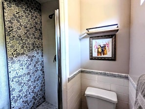 A bathroom with a shower, a toilet, and a framed picture on the wall. - Rustic Elegance by the Lake: Duplex Cabin Rental in Santa Ysabel (Santa Ysabel)