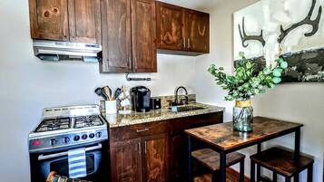 A compact kitchen with wooden cabinets, a gas stove, a sink, and a small dining table.