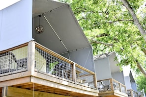 A multi-level building with balconies, a covered outdoor area, and a tree in the background.