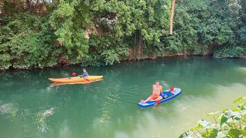 Two kayaks on a calm river surrounded by dense greenery.