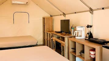 A tent with two beds, a kitchenette, and a small table.