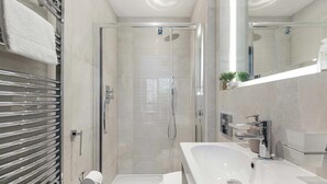 Een moderne badkamer met douche, toilet en wastafel.