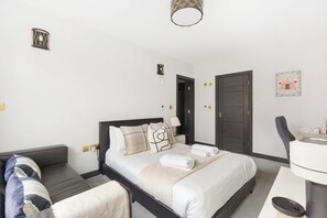 A hotel room with a bed, a sofa, a desk, and a chair.