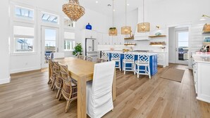 Uma cozinha ampla com armários brancos, uma ilha central e luminárias pendentes.