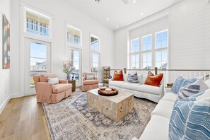 Un salón espacioso con un sofá blanco, dos sillones, una mesa de centro y ventanas amplias.