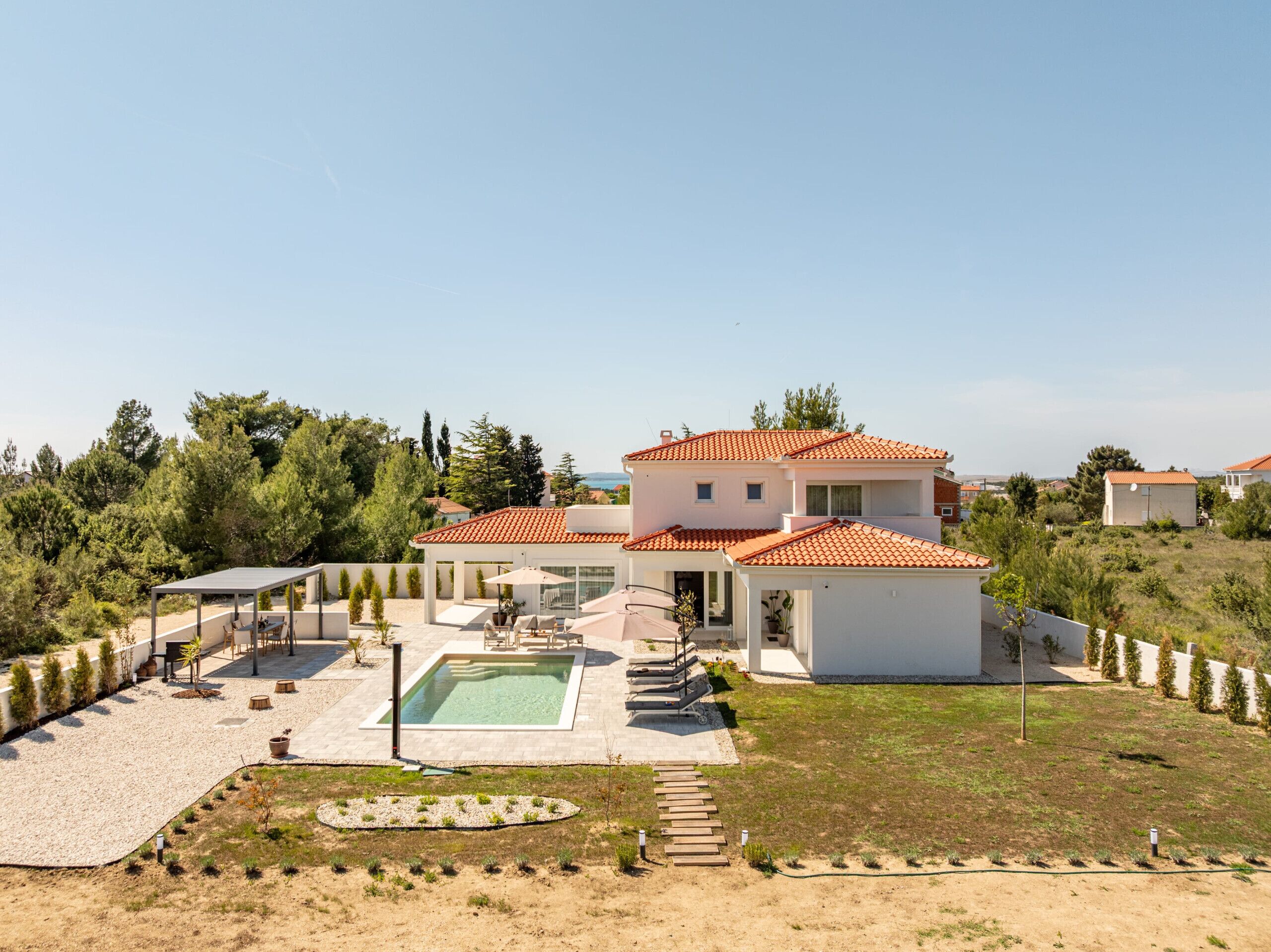 Ein zweistöckiges Haus mit Swimmingpool, Sitzgelegenheiten im Freien und Blick auf die umliegende Landschaft.