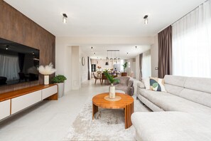 A modern living room with a sofa, coffee table, TV, and dining area. - Villa Emocija Zadarvilas (Vrsi)