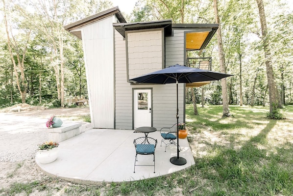 A modern house with a patio, a door, and a small outdoor seating area with two chairs and a table.