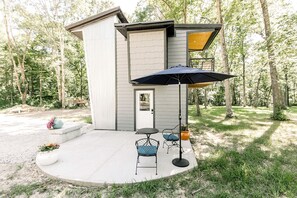 A modern house with a patio, a door, and a small outdoor seating area with two chairs and a table.