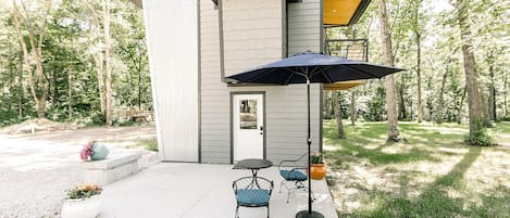Una casa moderna con un patio, una puerta y un pequeño espacio exterior con dos sillas y una mesa.