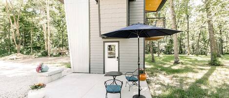 A modern house with a patio, a door, and a small outdoor seating area with two chairs and a table.