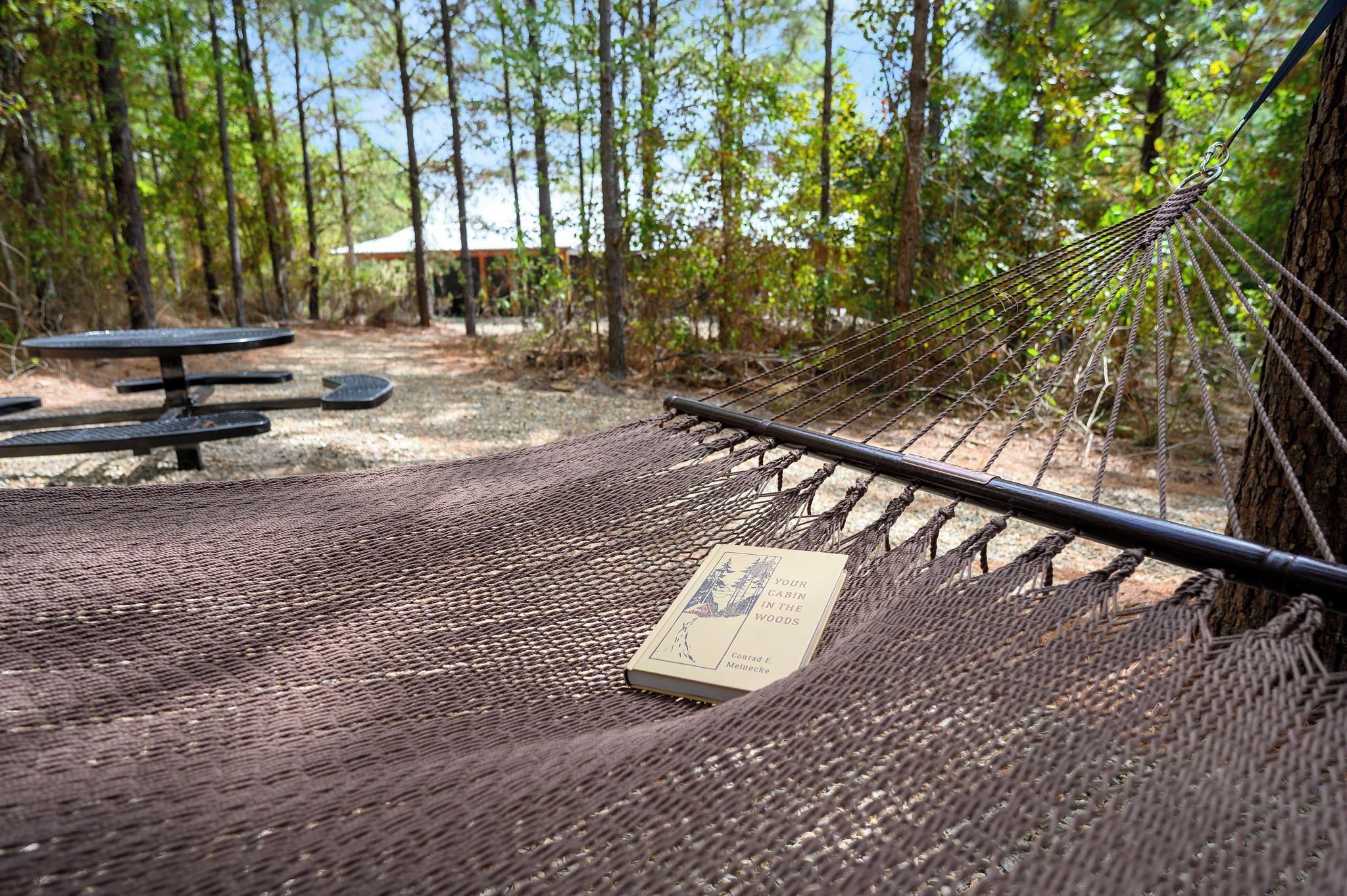 Una hamaca con un libro titulado 'Your Cabin in the Woods' de Conrad E. Melineck.