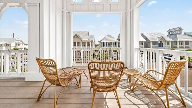 Un espacio al aire libre techado con muebles de mimbre y vistas a casas.