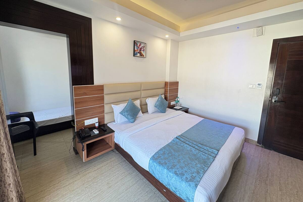 A hotel room with a bed, bedside table, nightstand, and a ceiling fan.