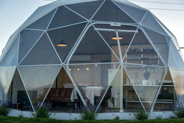 Estructura de domo geodésico con una mesa central y luces colgantes.