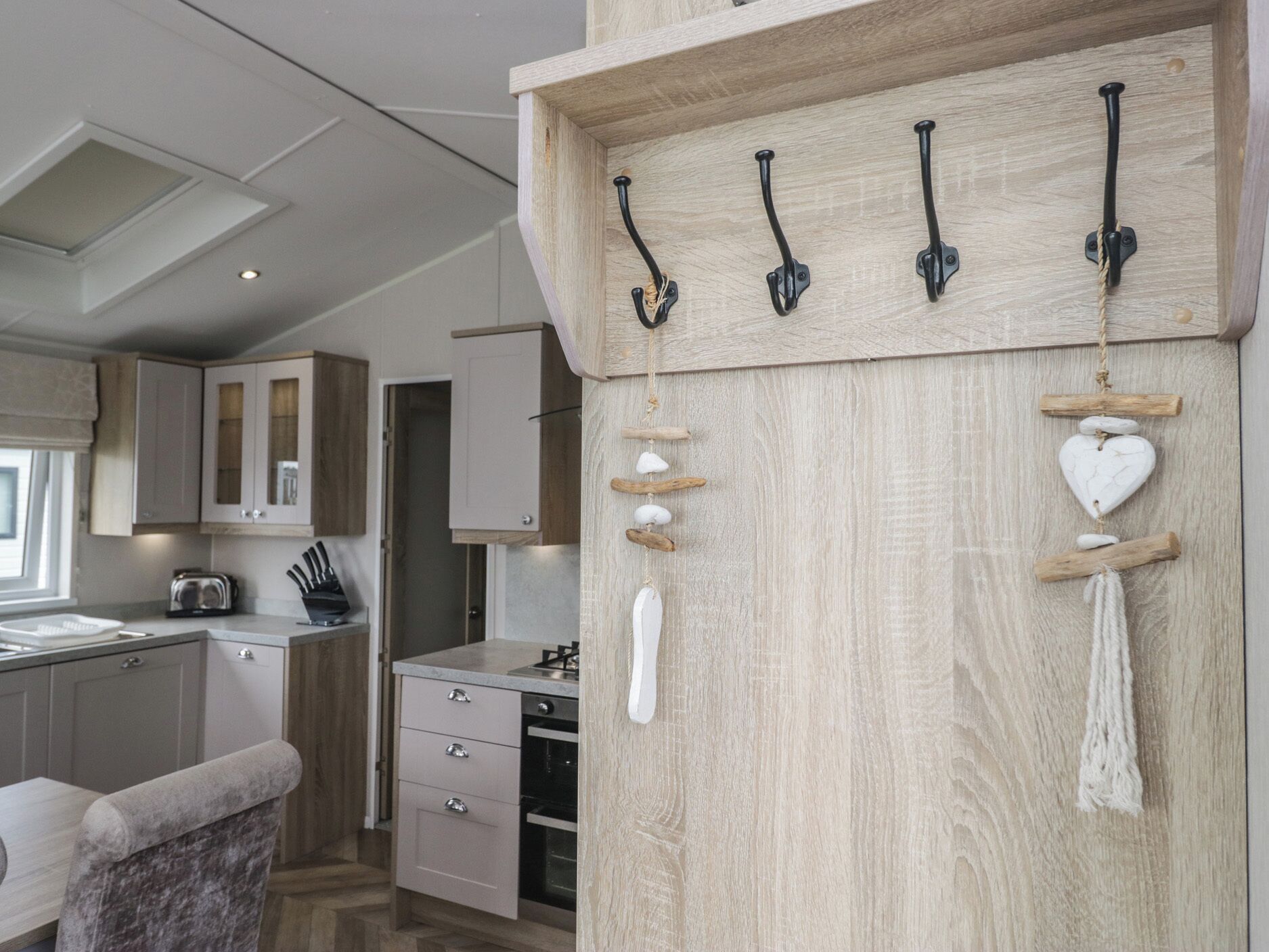 Eine moderne Küche mit Holzschränken, einem eingebauten Ofen und einer Wandleiste mit Haken und Dekorationselementen.