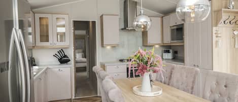 A modern kitchen with a wooden dining table, white cabinets, and pendant lighting.