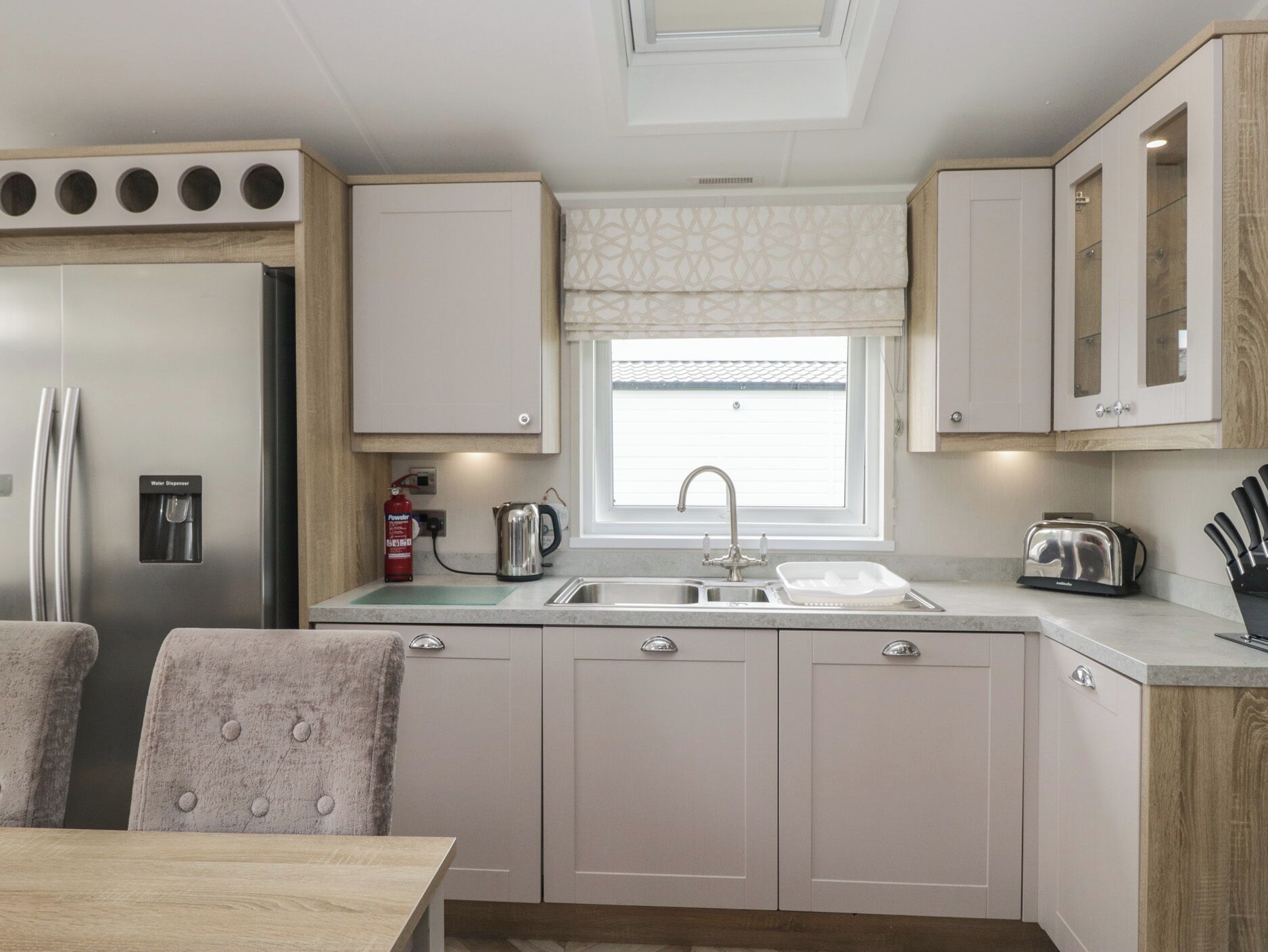 A compact kitchen with a refrigerator, sink, and a window above the countertop.