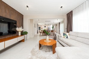 Ein modernes Wohnzimmer mit Sofa, Couchtisch, Fernseher und Essbereich.