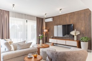 Ein modernes Wohnzimmer mit einer Couch, Sesseln, einem Couchtisch und einem Fernseher.