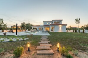 Ein modernes Haus mit Pool, Terrasse und gepflegtem Rasen.