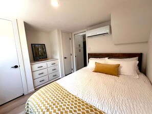 Ein Schlafzimmer mit Bett, Kommode, Kleiderschrank und Klimaanlage.