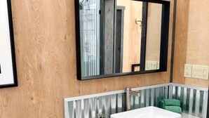 A modern bathroom with a wooden vanity, a large mirror, and a wall-mounted light fixture. - Secluded Montana Dome Retreat with Stunning Mountain Views Near Yellowstone National Park (Park County)