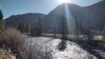 A river with sunlight reflecting off the water, surrounded by trees and mountains.