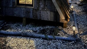 Eine Holzhütte mit einem dreieckigen Dach und einem großen Fenster.