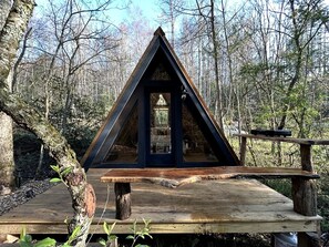 A wooden deck with a triangular wooden structure, possibly a gazebo or shelter, surrounded by trees. - Secluded Off-Grid Cabin Retreat with Fire Pit & Sauna in Zirconia, North Carolina (Zirconia)