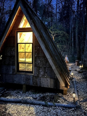 Una cabaña de madera con techo triangular y un ventanal grande.