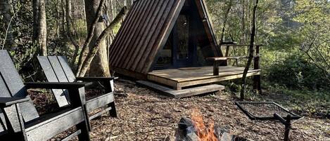 Une cabane avec un toit en pente, un foyer et un banc.