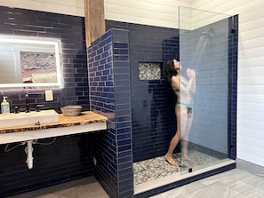 Un baño con ducha, lavamanos y espejo.