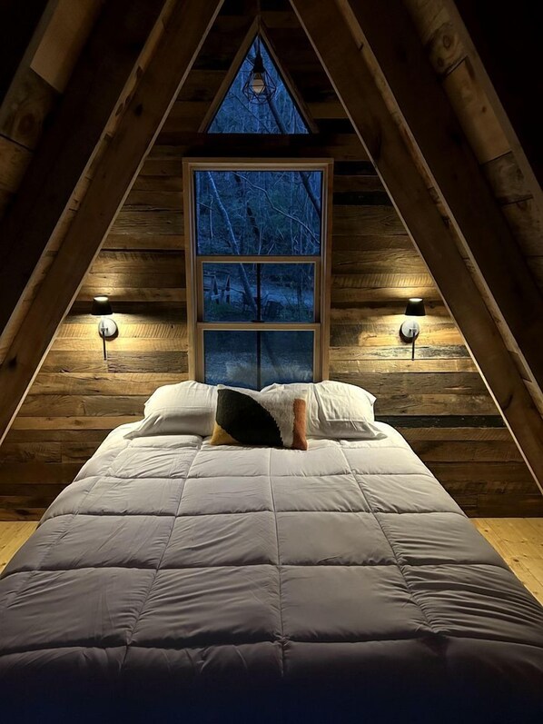 A bedroom with a bed, a window, and two wall-mounted lamps. - Secluded Off-Grid Cabin Retreat with Fire Pit & Sauna in Zirconia, North Carolina (Zirconia)