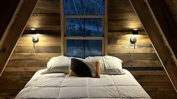 A bedroom with a bed, a window, and two wall-mounted lamps.