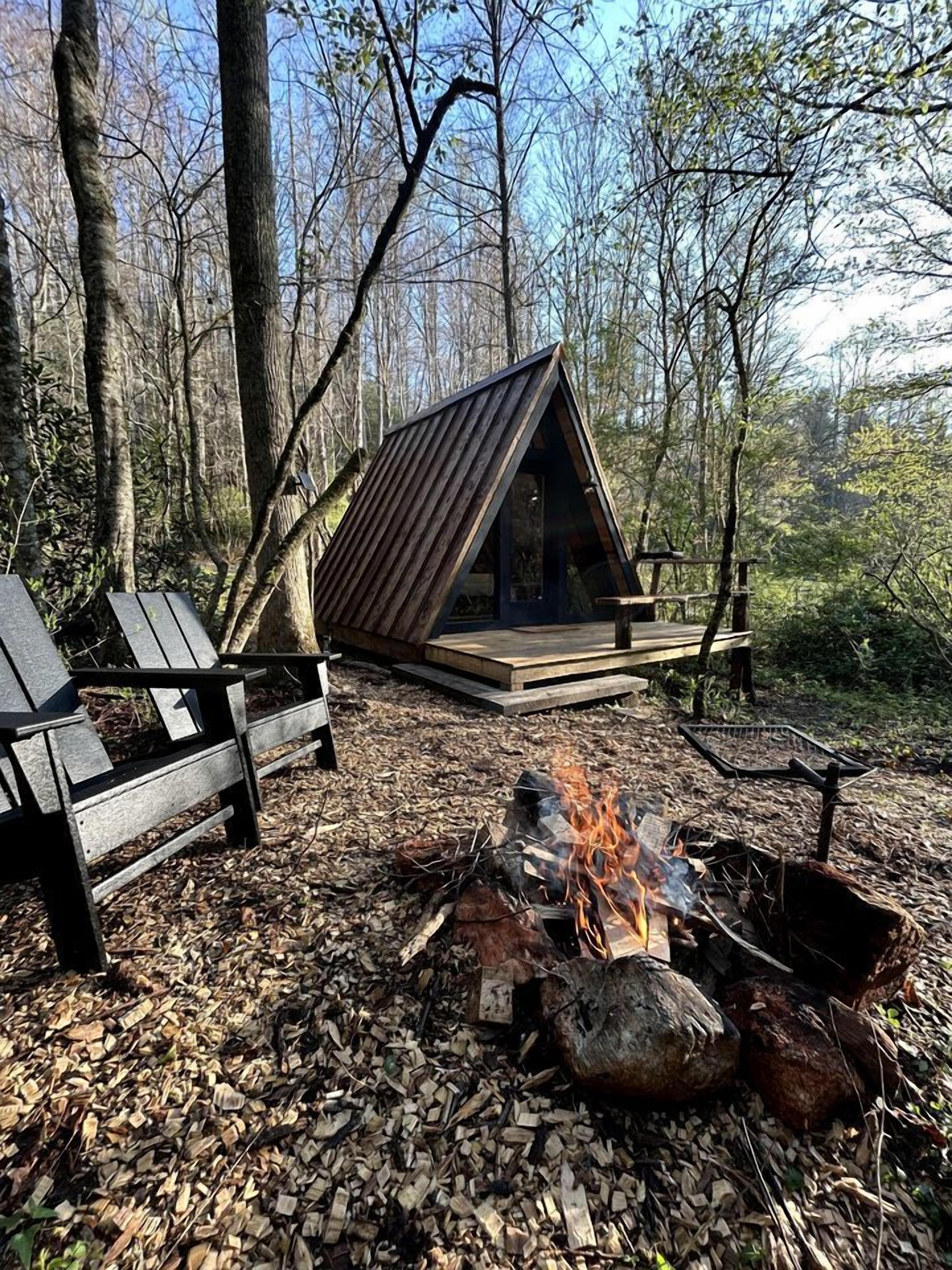 Eine Hütte mit geneigtem Dach, einem Feuerkorb und einer Bank.