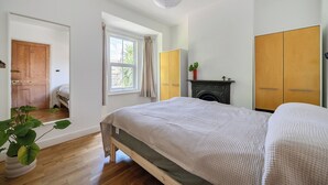 A bedroom with a bed, a window, a wardrobe, and a fireplace. - Victorian Terrace Near Uni, Sleeps 6, Garden (Reading)