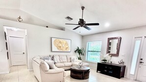 A spacious living room with a sectional sofa, a coffee table, and a ceiling fan.