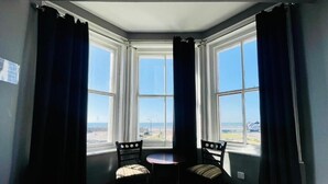 A corner room with a bay window, a small round table, two chairs, and a view of the landscape.