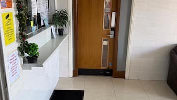 A reception area with a wooden door, a reception desk, and a black mat on the floor.