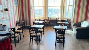 A dining area with striped wallpaper, wooden flooring, and a view through large windows.