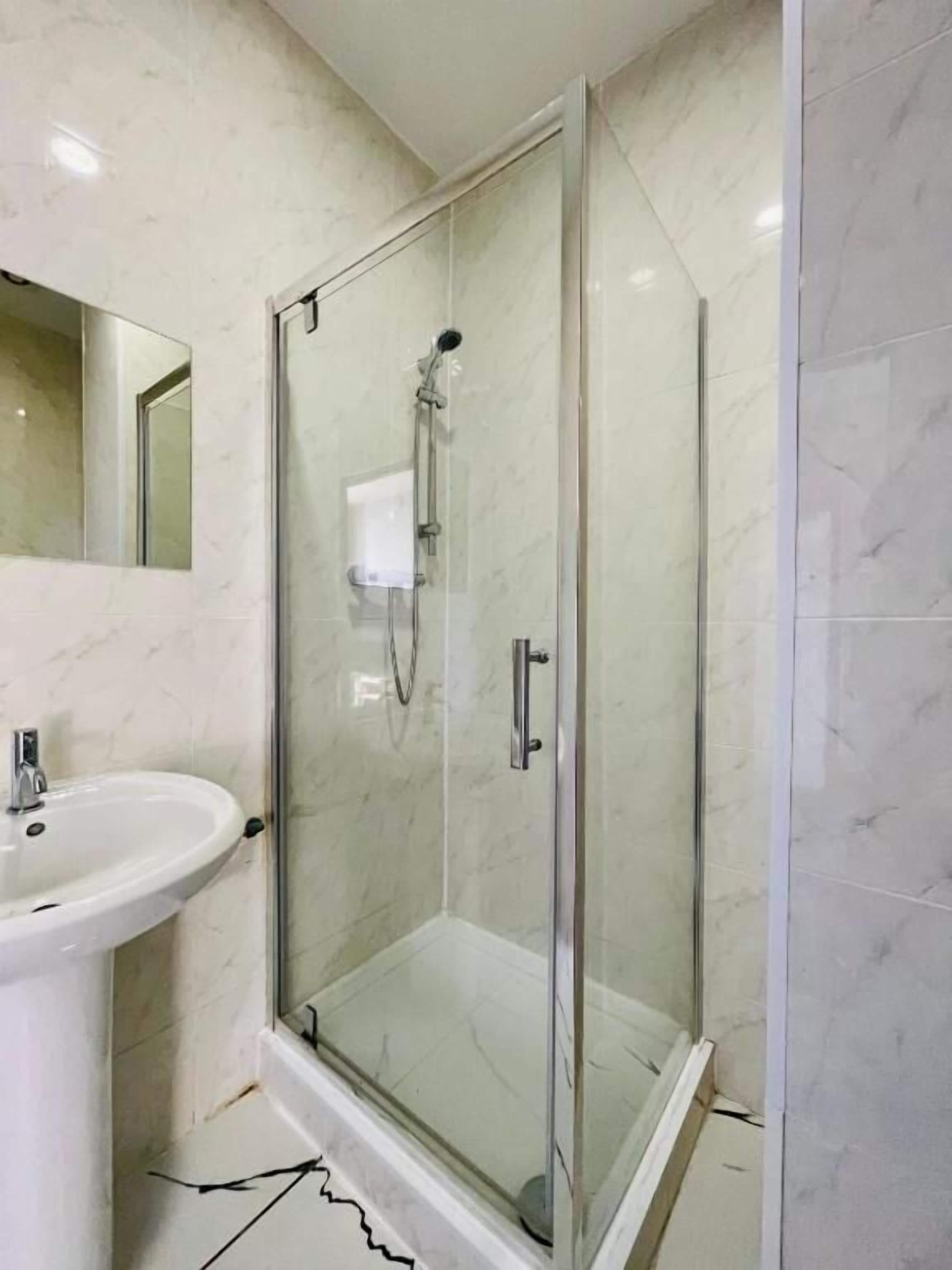 A bathroom with a glass-enclosed shower, a sink, and a mirror.