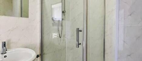 A bathroom with a glass-enclosed shower, a sink, and a mirror.