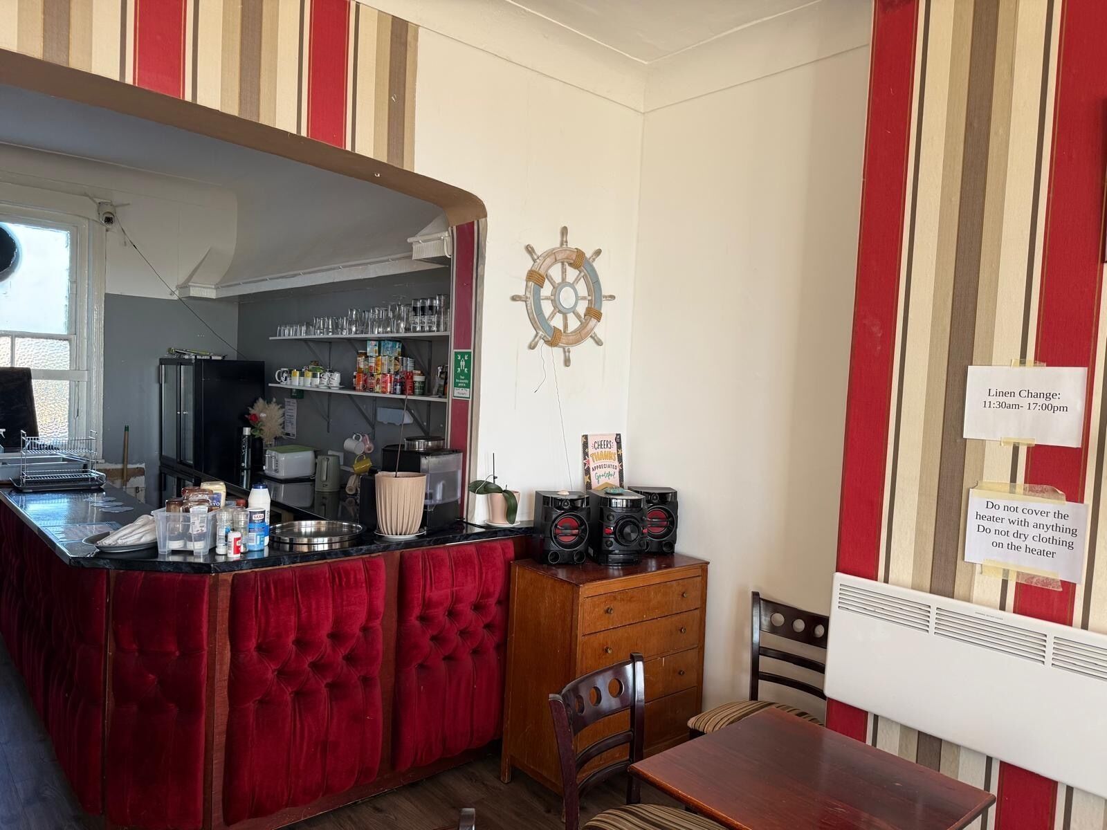 A kitchen with striped walls, a bar area, and a ship's wheel decoration.