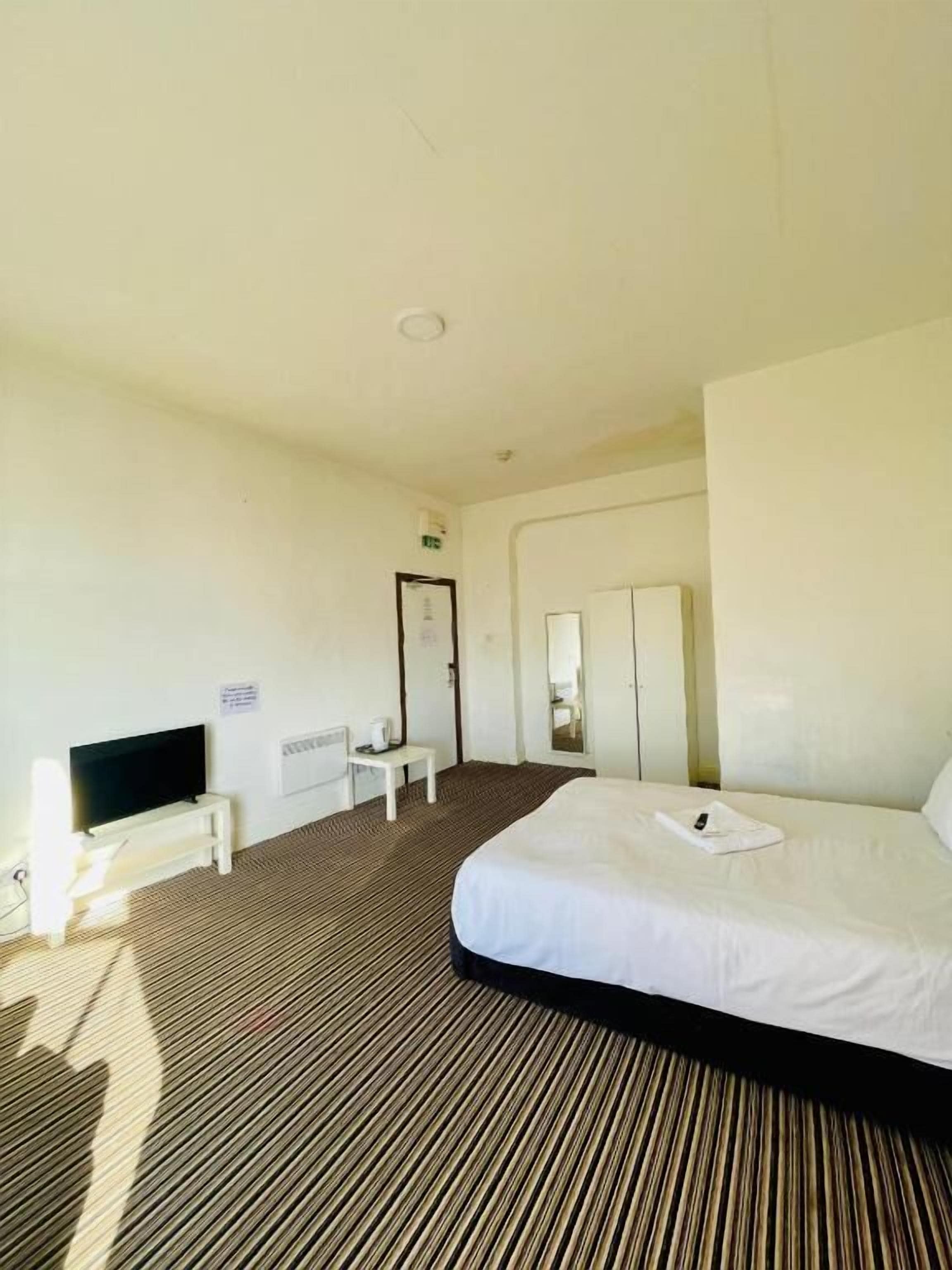 A hotel room with a bed, a TV, a desk, and a wardrobe.