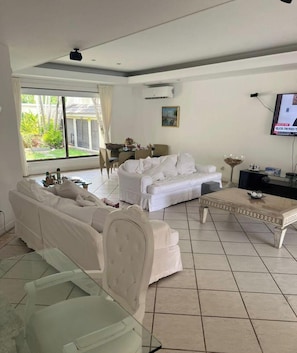 Ein Wohnzimmer mit einem weißen Sofa, einem Couchtisch und einem Fernseher.