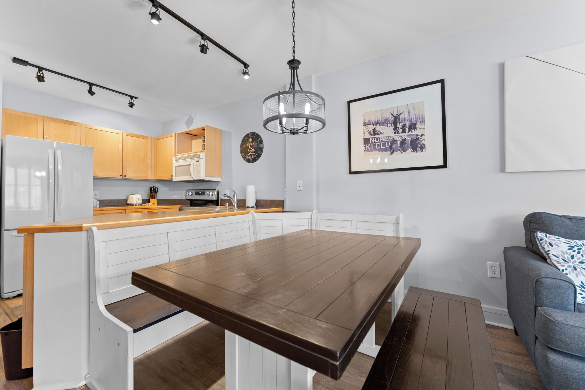 Gather around the spacious dining table where meals become memories. The open kitchen with its breakfast bar and modern appliances makes cooking a joy, while warm wood tones invite you to relax.