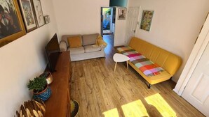 Un salon comprenant un canapé, une table basse, un plancher en bois et une porte donnant sur une autre pièce.