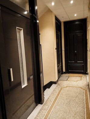 A hallway with a dark door, a light-colored wall, and a patterned carpet. - HOME FOR 2 FEW STEPS FROM CASINO MONTE CARLO AND BEACH (Beausoleil)